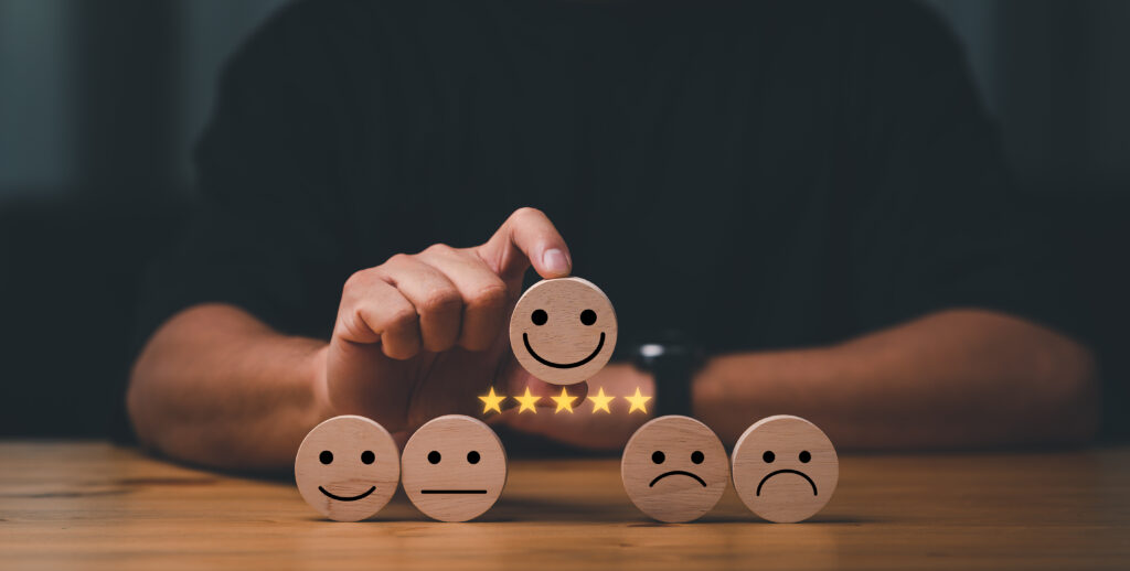 Hand of a businessman chooses a smile face on wood block cube to represent member satisfaction