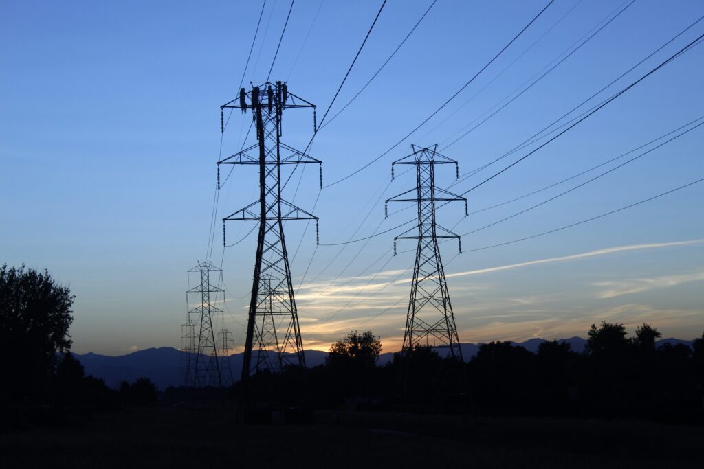 power lines with blue sky and sun setting representing MHHS