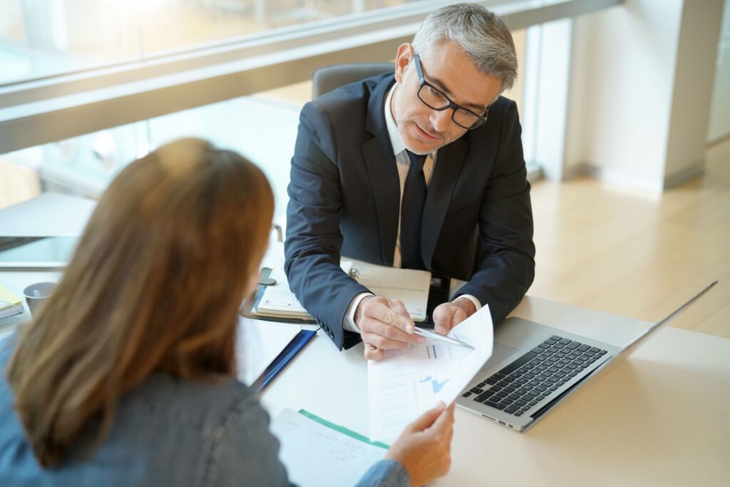 Woman in office with man signing document representing being compliant