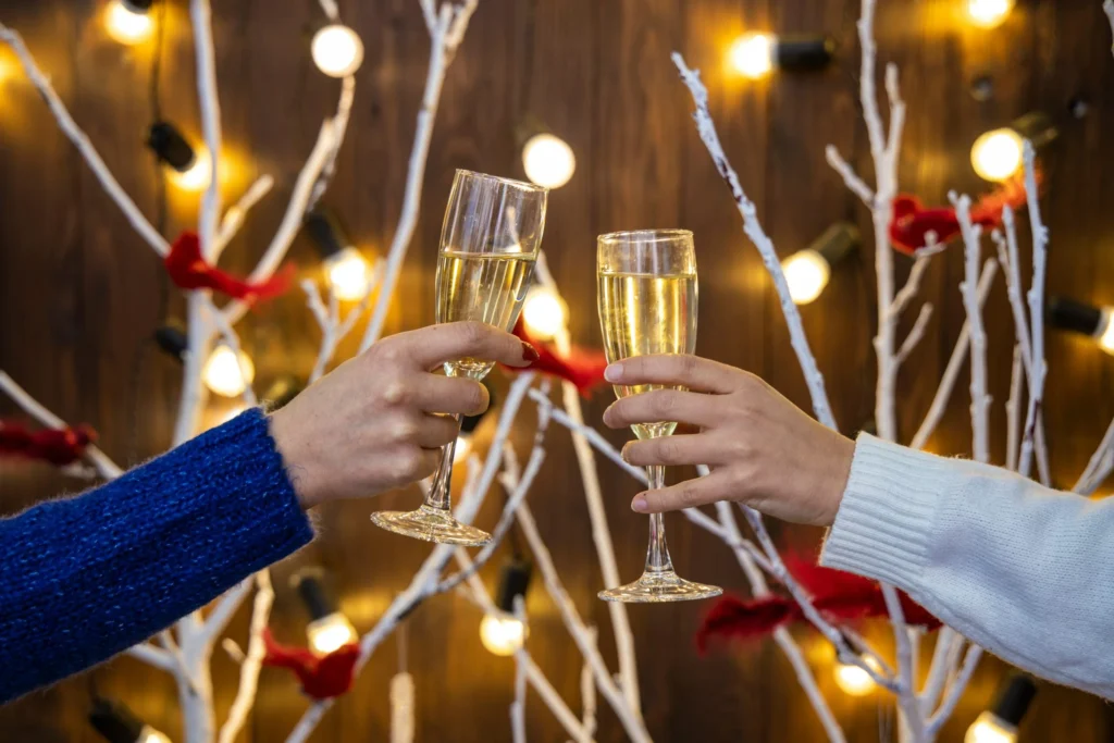 Two filled champagne glasses being toasted at a Christmas party