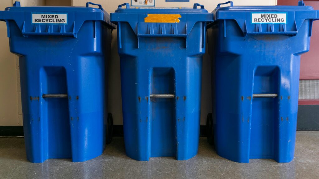 Three blue recycling bins lined up representing waste collection