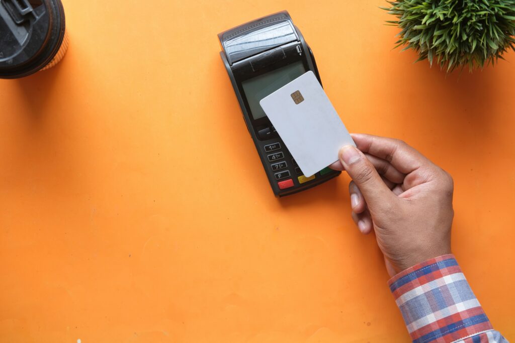 man making contactless payments on card machine with an orange background